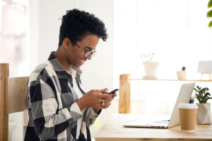 Smiling black woman receiving good news texting message on phone